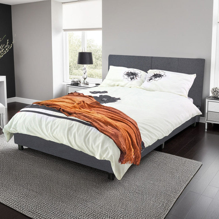 A New York Fabric Bed Frame in a modern bedroom setting, upholstered in soft grey fabric with a padded headboard, on a slatted base.