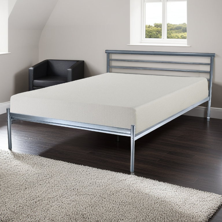 A silver metal bed frame with a headboard and footboard, placed in a room with a mattress on it, alongside a nightstand and a chair.