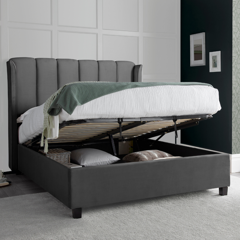 Grey upholstered bed with storage compartments in a room setting.
