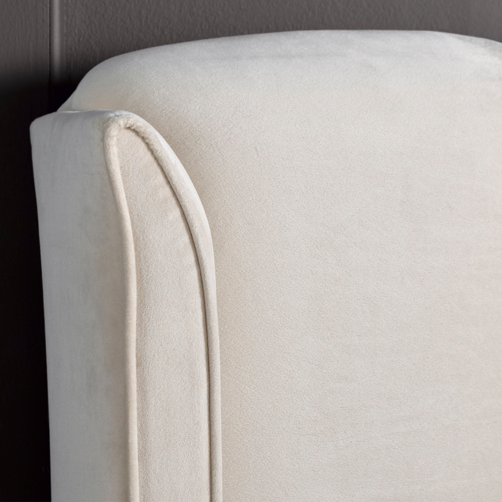 Close-up of a beige upholstered chair with a dark background