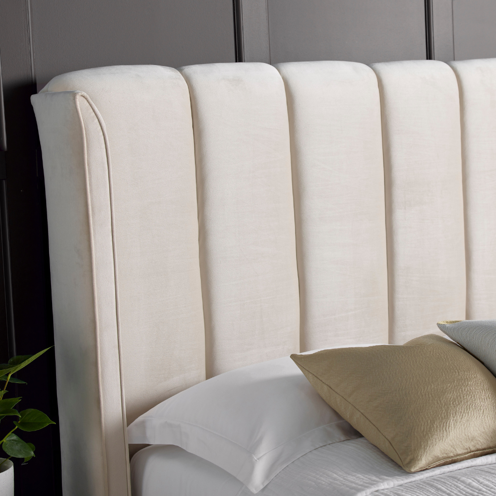 Beige upholstered headboard with pillows on a bed in a bedroom setting