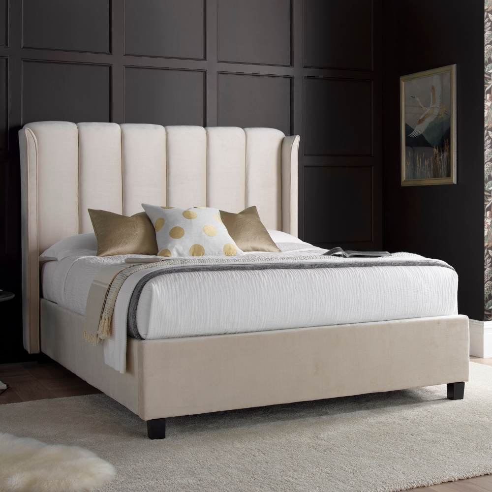 Beige upholstered bed with white bedding and decorative pillows in a bedroom setting.