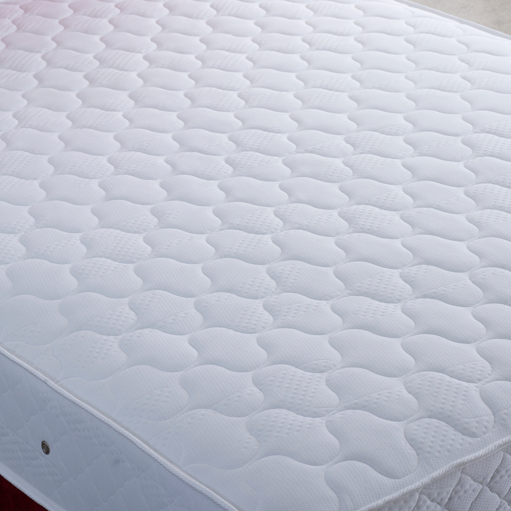 Close-up of a white quilted mattress cover with a diamond pattern.