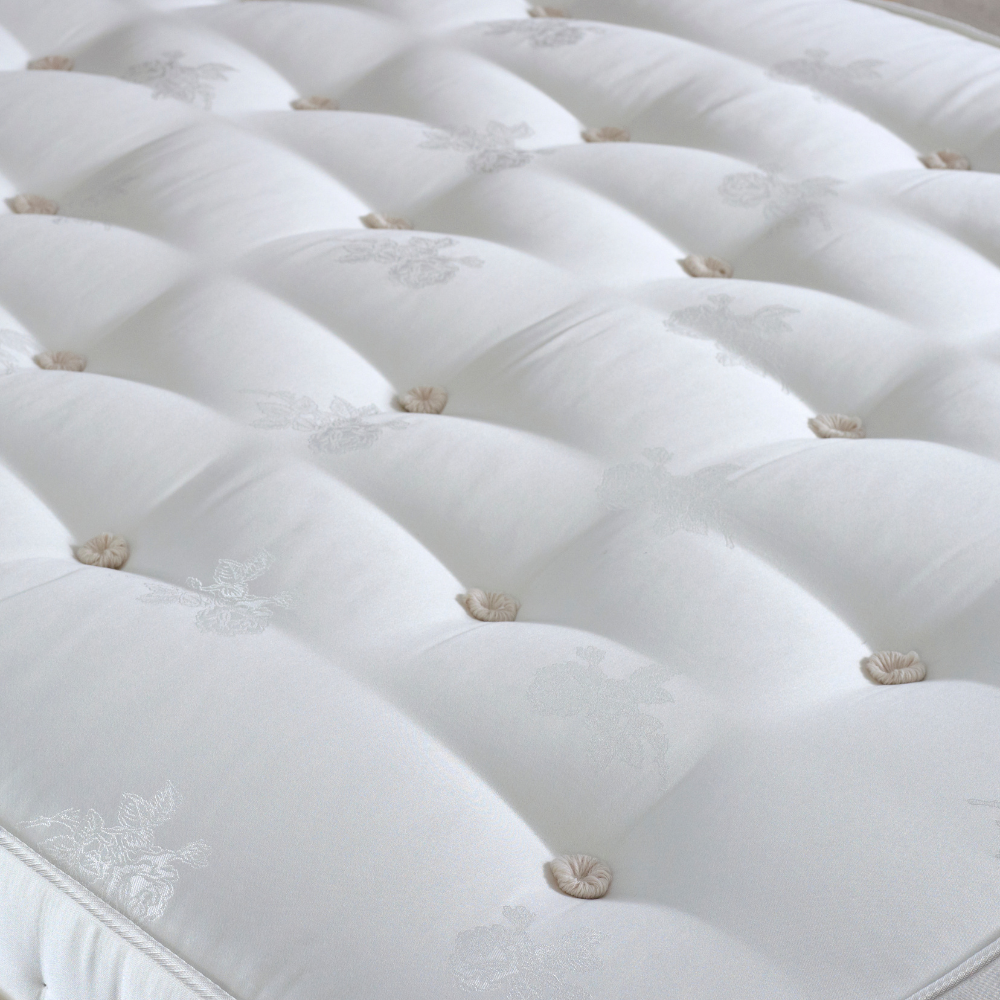 Close-up of a white mattress with tufted design and decorative buttons.