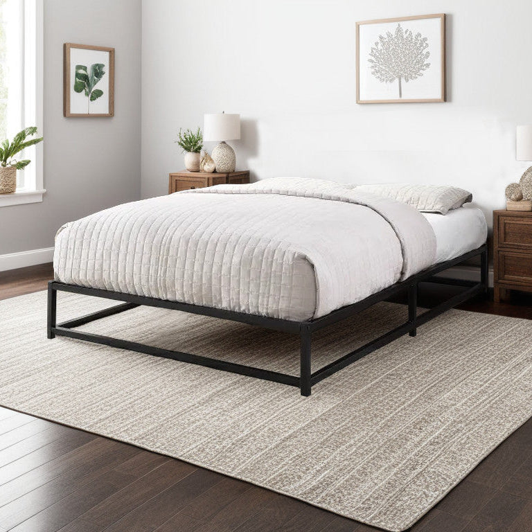 A metal platform bed frame in a minimalist design, with a white mattress on it, placed in a room with a gray rug, wooden floor, and decorative wall art.