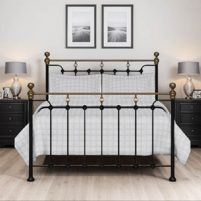 A black and gold Edinburgh Metal Bed Frame with a king-size, placed in a room with a white carpet, wooden floor, and decorated with a framed picture on the wall.