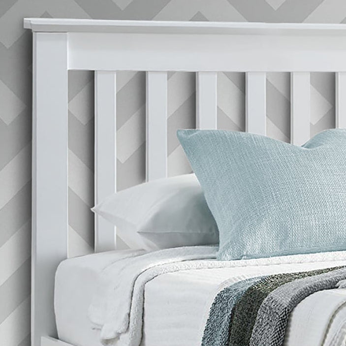 Bed with white headboard and light blue pillow against a grey geometric patterned wall.