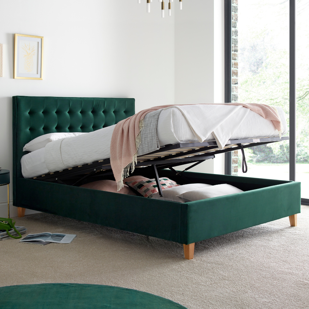 Green upholstered ottoman bed frame opened in a white bedroom.