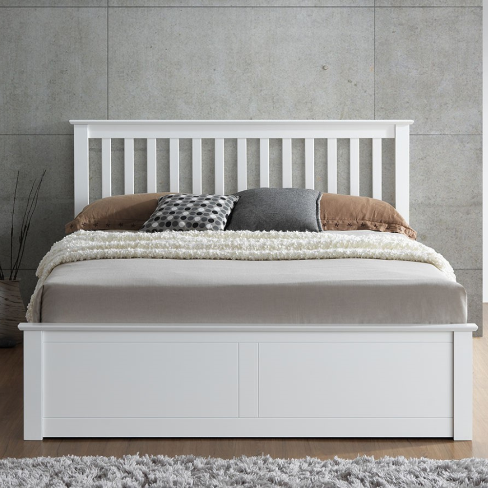 White wooden bed with bedding against a grey wall