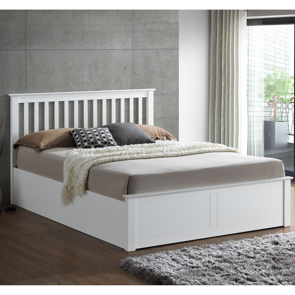 White bed with bedding in a room with a concrete wall and window.