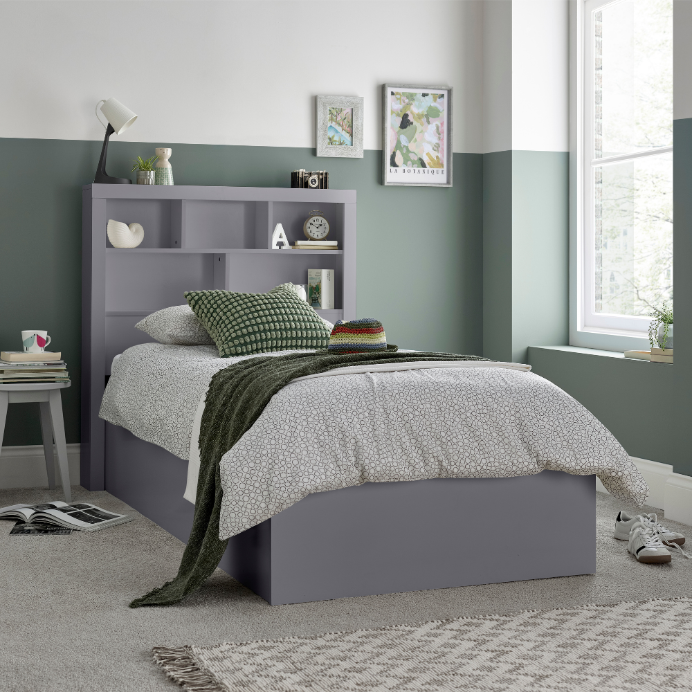 Grey bed with bookshelf headboard in a room with green walls and a window.