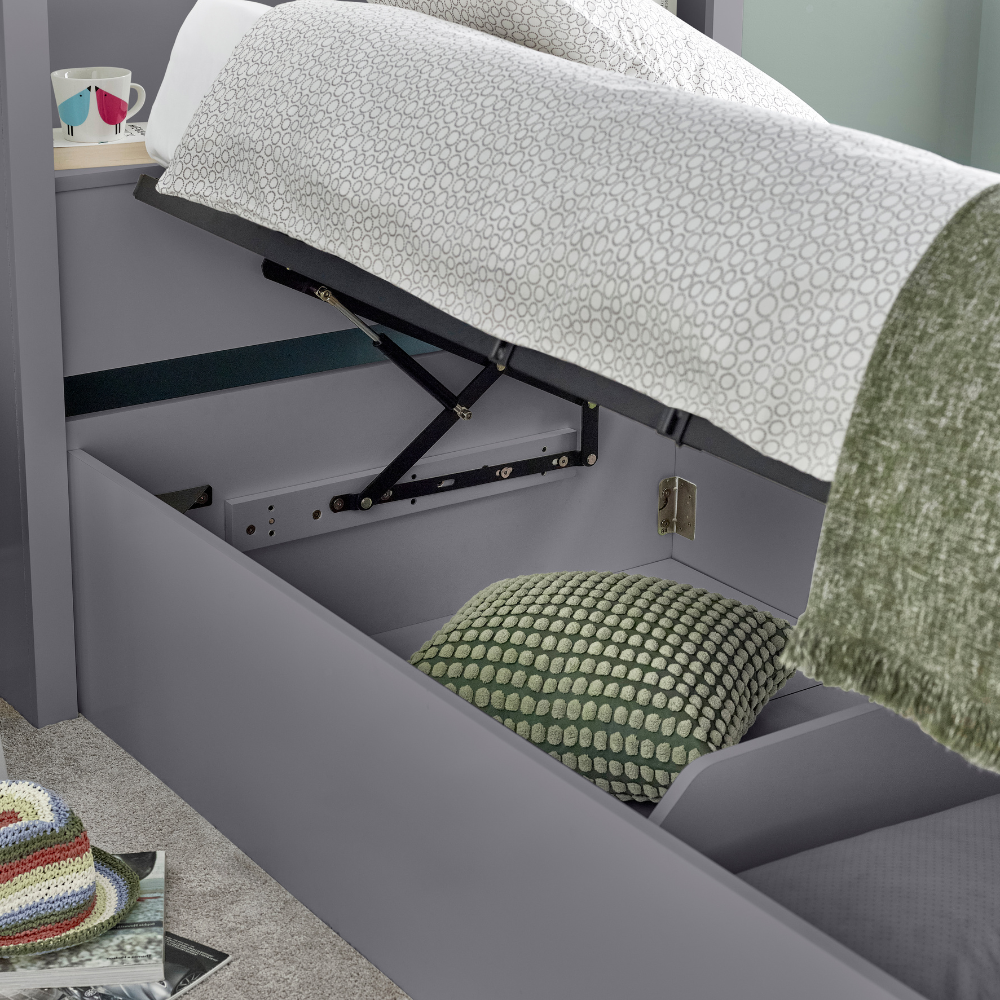 Grey bed with a lift mechanism and white mattress, green pillow, and colorful blanket.