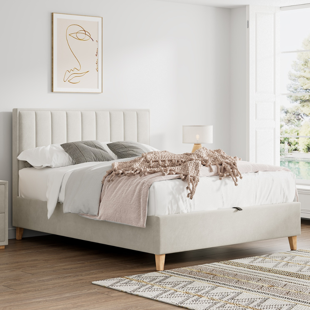 Neatly made bed with beige headboard in a bright bedroom