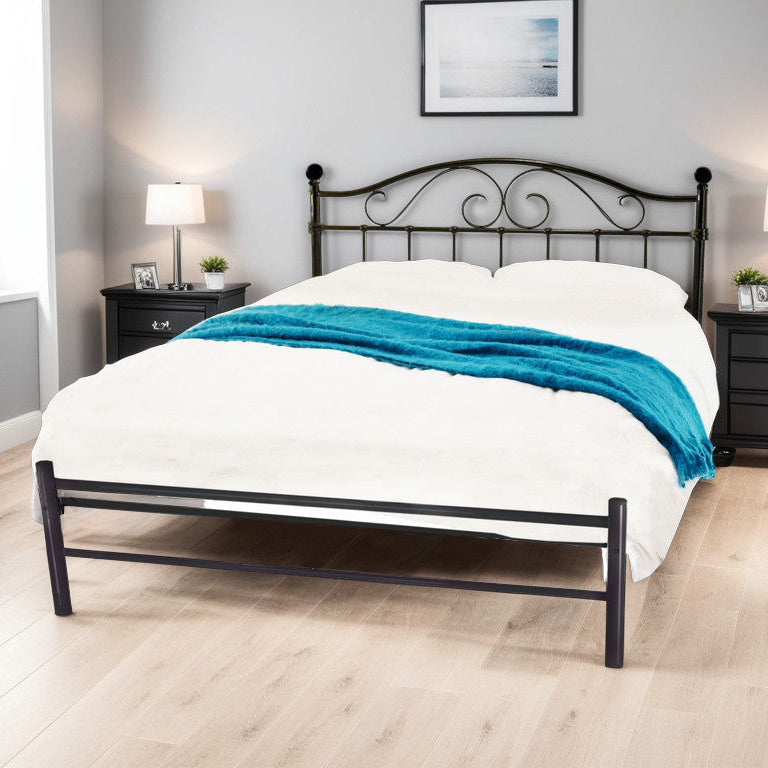 A black metal bed frame with cross-bar detailing, displayed in a bedroom setting with bedding and side tables.