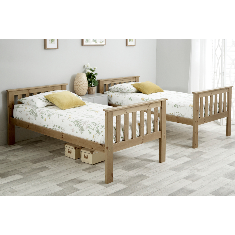 Two wooden beds with storage drawers in a room with a light gray floor and white walls.