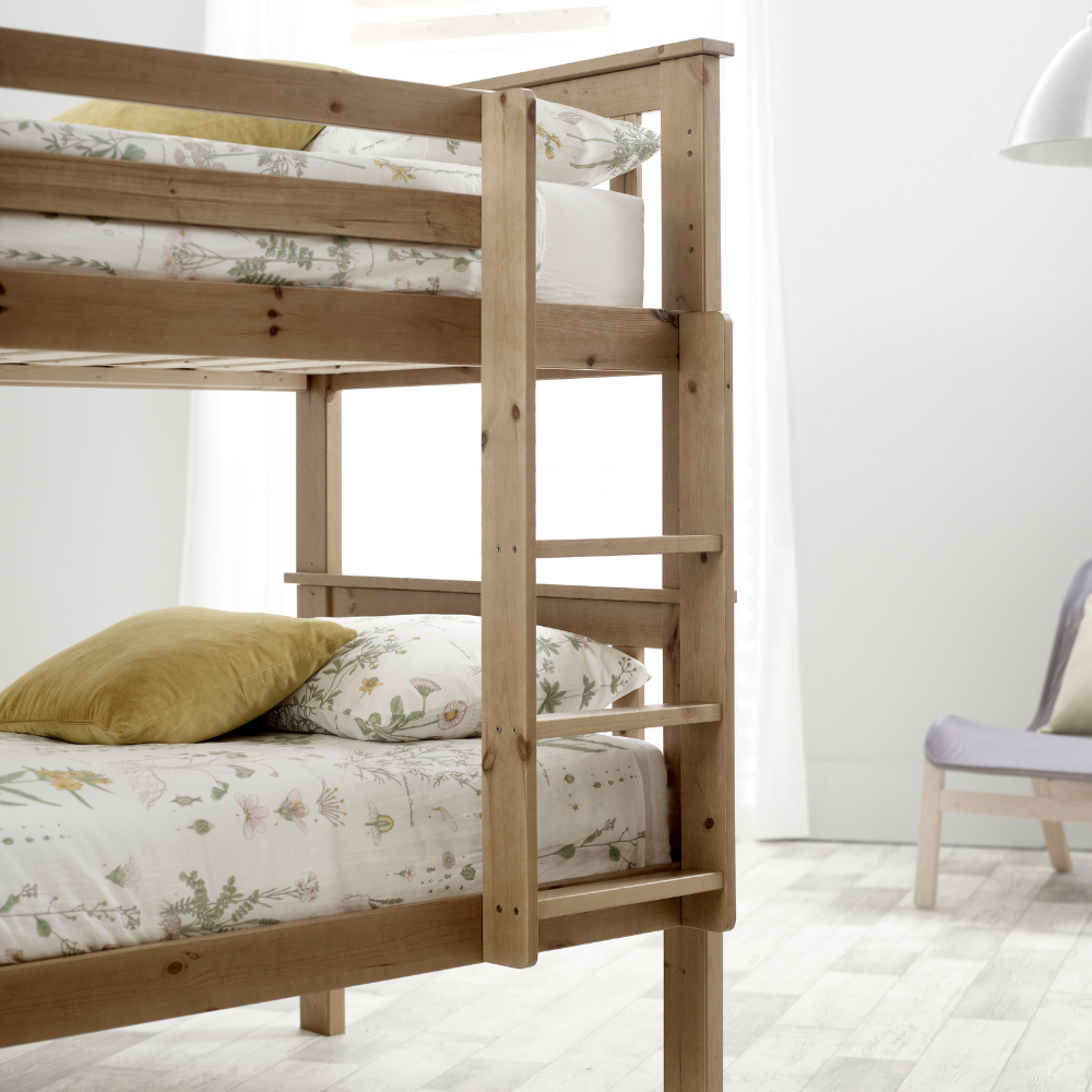Wooden bunk bed with floral bedding in a minimalistic room.