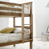Wooden bunk bed with floral bedding in a minimalistic room.