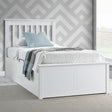 White bed with grey bedding against a geometric-patterned wall