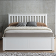 White wooden bed with bedding against a grey wall