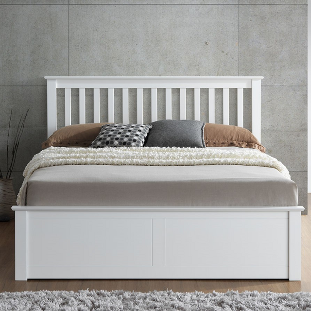 White wooden bed with bedding against a grey wall