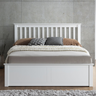 White wooden bed with bedding against a grey wall