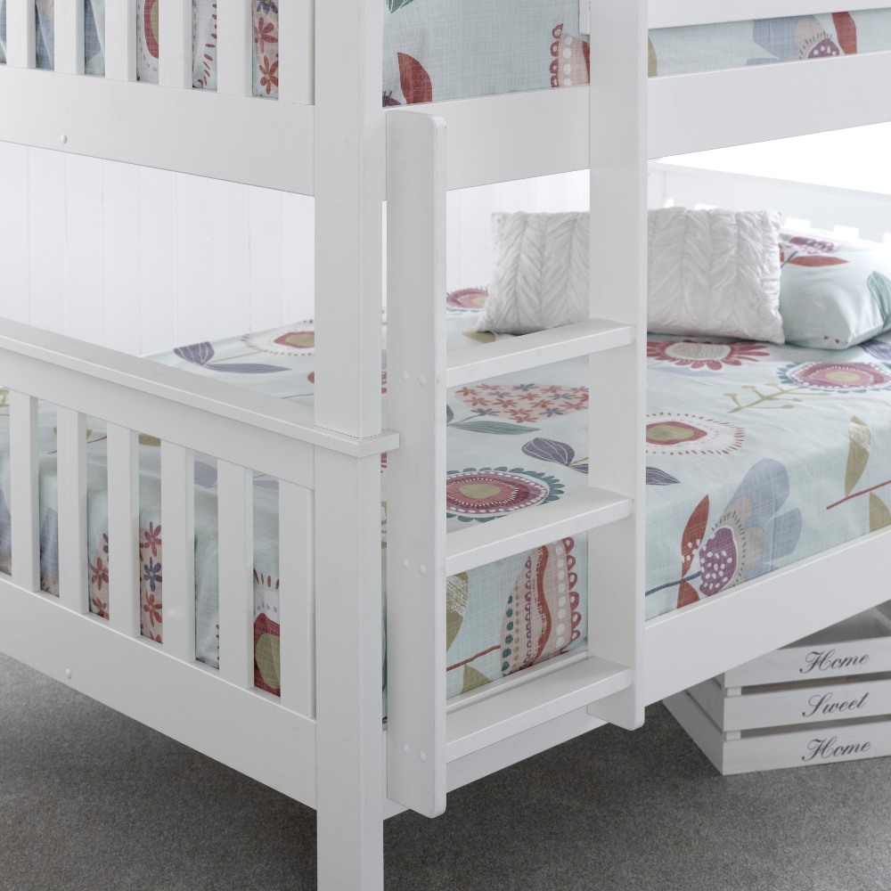 White bunk bed with floral bedding on a grey floor